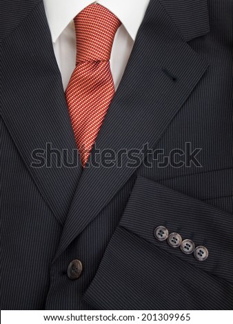 detail of mens pinstripe suit jacket lapel and sleeve buttons with  shirt and orange speckled tie