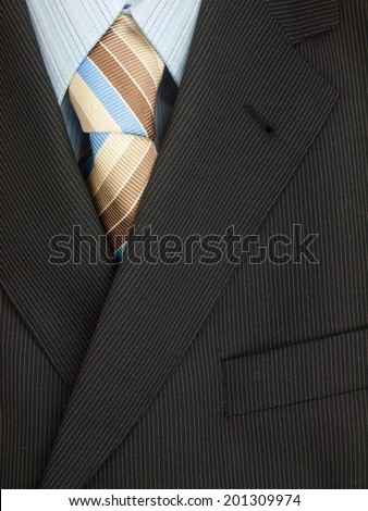 detail of mens pinstripe suit jacket with  shirt and brown and blue colored striped tie