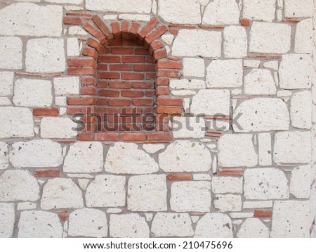 detail  of red brick portal  in a reproduction aged stone wall with grey stonework red tiles and dark grey mortar