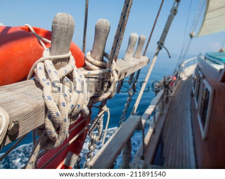 detail of tied off rope with stays and life ring on a traditional wooden sailing boat at sea