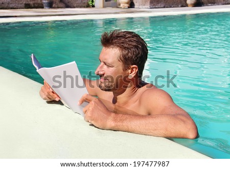 beautiful man reading a magazine by the pool