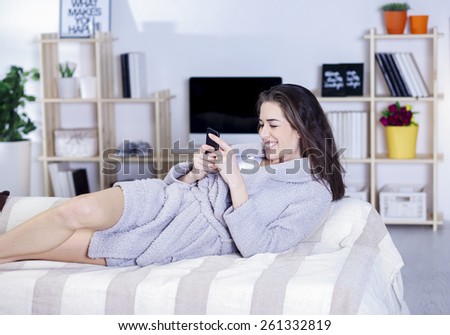 Beautiful woman in bed having tablet, computer and laughing, Woman in bed texting messages with  tablet and laughing in living room