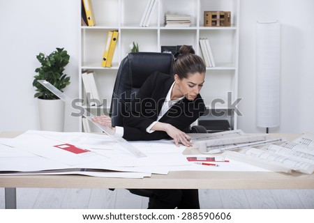 Female Architect Studying Plans In Office. Woman architect working in her office