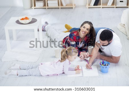 Young parents playing with their daughter in the living room. Family time