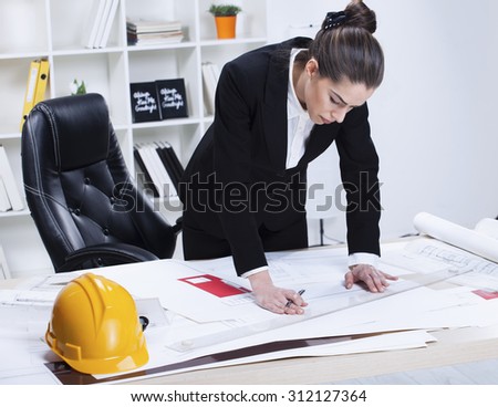 Female Architect Studying Plans In Office. Woman architect working in her office