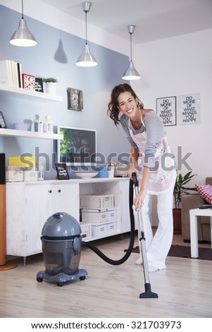 Young excited woman cleaning with a vacuum cleaner