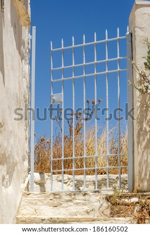 Iron gates halfway opened leading into deserted garden, Greece