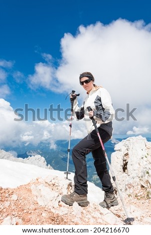 Young girl ascending a mountain with trekking poles and mountain view in the back