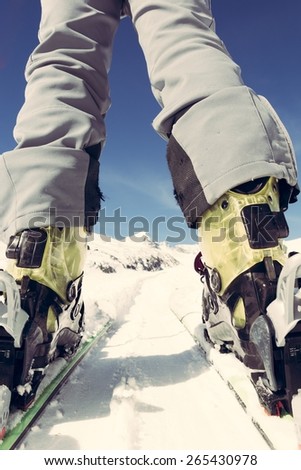 Close up of skier\'s boots and skies from unusual angle. Mountain peak in the background.