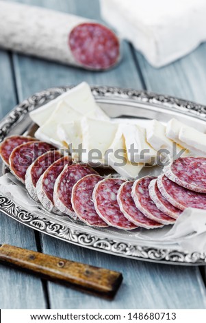 Pieces of brie cheese and air dried salami on a tray