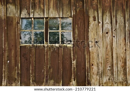 Old antique barn with double window panes reflecting trees in field. Barn is over one hundred years old. /Old antique weathered barn with windows reflecting tree
