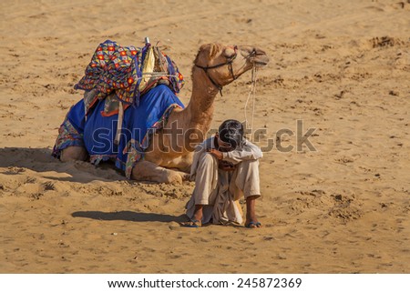 Jaisalmer, India - February 25, 2013: Cameleer at the Sam Sand Dune. Camel riding activity for tourists is another income source for desert villagers apart from farming and animal raising