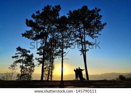 A happy couple standing in the sunrise morning with silhouete landscape style