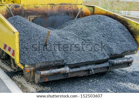 Back view of a large asphalt paving machine full of fresh asphalt.