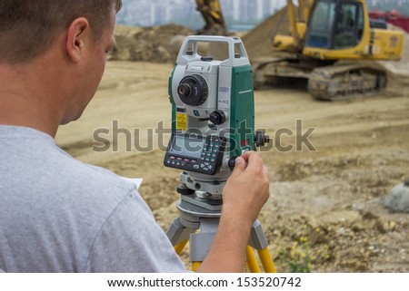 Land surveyor working with total station at construction site
