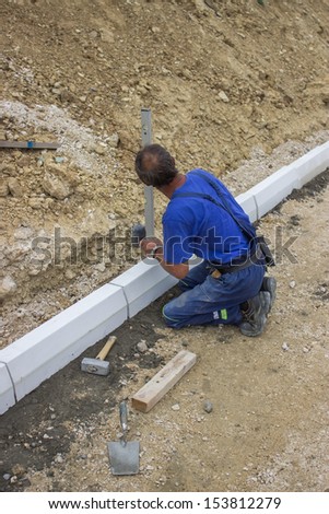 manual worker works with a level, worker leveling concrete curbs of new sidewalk