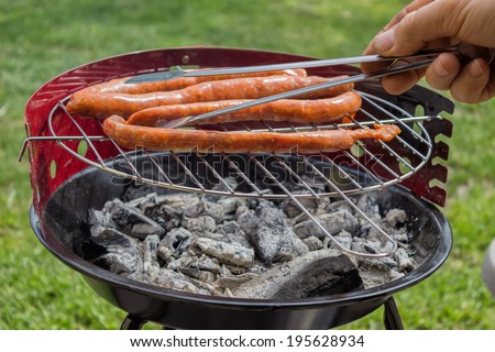 Man Preparing Sausage on Outdoor Grill. Selective focus.