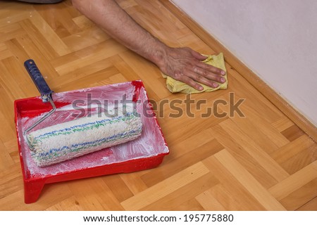 Man cleaning floor after painting wall with roller
