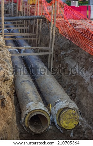 Pipes in trench, industrial pipeline. Insulated pipes to connect a new buildings on heat system. One insulated pipe carries hot water, another carries cool water.