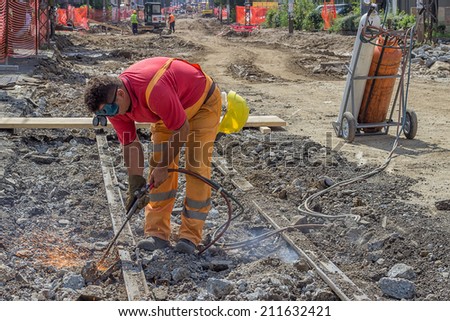 BELGRADE, SERBIA - AUGUST 09: Demolition of tram lines, works on the demolition tram tracks. Using oxyacetylene cutting torch to cut tracks. Selective focus. At street Vojvode Stepe in August 2014.