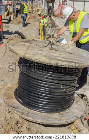 BELGRADE, SERBIA - SEPTEMBER 30: Installing new ground infrastructure in the street. Workers unrolls electrical cable. Selective focus. At street Vojvode Stepe in September 2014.