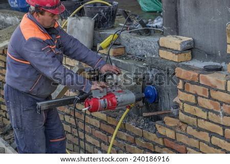 BELGRADE, SERBIA - DECEMBER 24: Worker with core drill, drilling penetration on concrete wall for pipe. Selective focus. At construction site in December 2014.