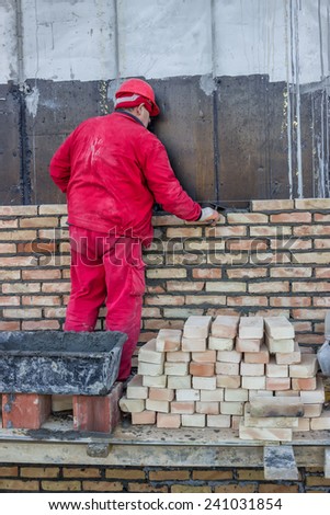 BELGRADE, SERBIA - DECEMBER 27: Mason spread a mortar bed joint for building brick. Bricklaying spreading a bed Joint. Selective focus. At construction site in December 2014.