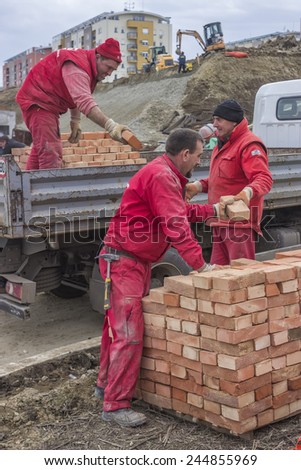 BELGRADE, SERBIA - JANUARY 17: Workers unload trucks with clay bricks, builder workers teamwork. At  construction site in January 2015.
