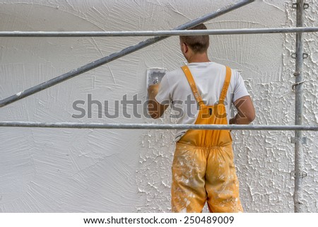 BELGRADE, SERBIA - AUGUST 28: Worker applying decorative top coat plaster with a trowel. Selective focus. At construction site in August 2014.