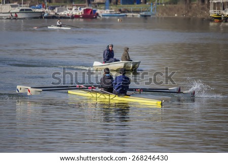 BELGRADE, SERBIA - MARCH 20: Rowing boat scull crew and coach in boat train on the River. Double sculls trailing. Focus on double scull boat and shallow dof. At Sava river in March 2015.