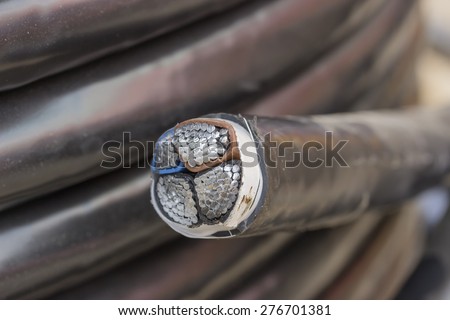 Cross section of black industrial underground cable on large wooden reel. Four core al cable. Selective focus and shallow dof.