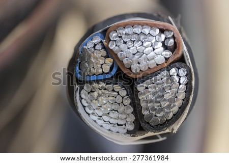 Cross section of black industrial underground cable on large wooden reel. Four core al cable. Selective focus and shallow dof.