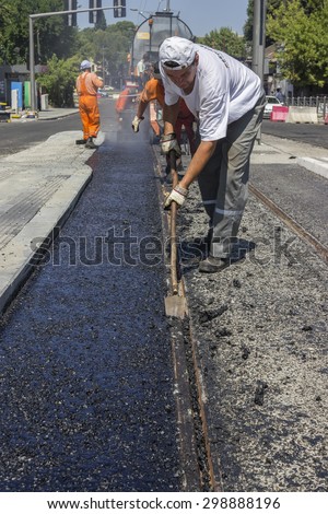 BEOGRAD, SERBIA - JULY 16, 2015: Crew laying asphalt mastic surface, during street repairing works. Selective focus and shallow dof.