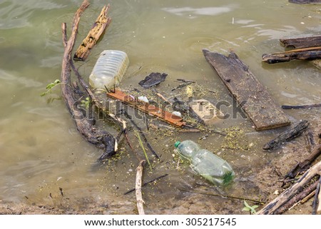 Plastic bottles and garbage waste on the shore of a river. Selective focus.