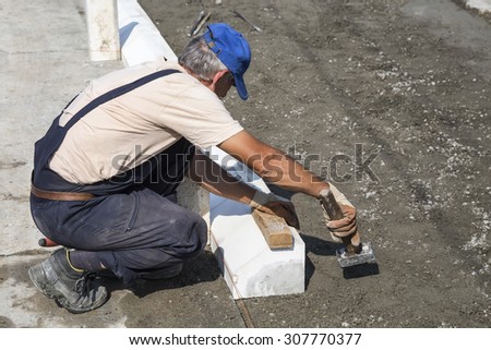 BEOGRAD, SERBIA - JULY 30, 2015: Worker using hammer for paving work. Selective focus and shallow dof.
