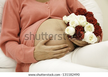 Pregnant woman holding a flower on the side and then using the hand to a child\'s love for flowers, and more