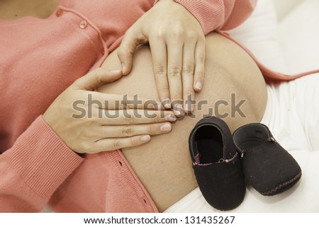 Pregnant woman making a heart shape on the hand to show their love for the child