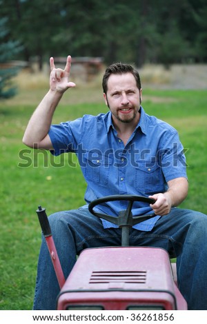 Man on riding lawn mower, rocking out, having a good time.