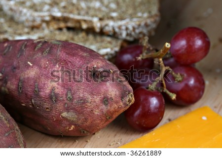 Food display of yams, grapes, cheese, and bread.