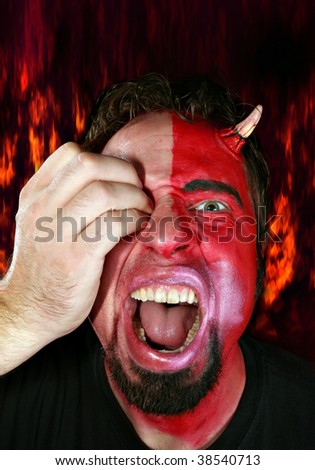 Half devil monster man being attacked by a hand gouging his eye.  Fire flames in the background.