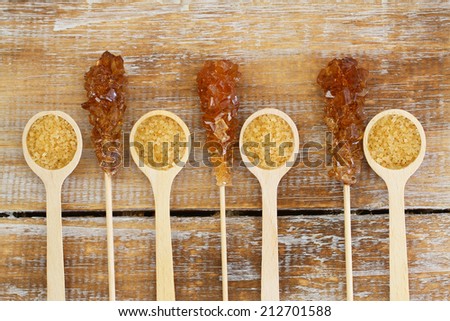 Brown sugar on wooden spoons and brown sugar sticks on wooden surface
