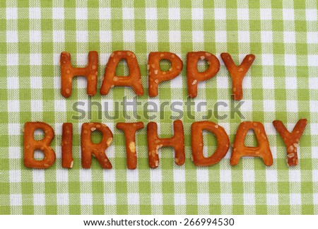 Happy birthday written with pretzel letters on checkered cloth