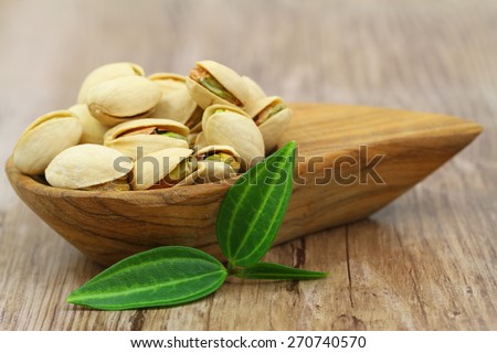 Pistachio nuts in bamboo bowl on wooden surface