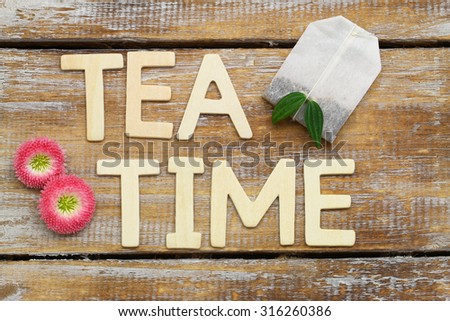 Tea time written with wooden letters on rustic surface