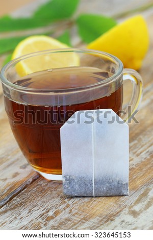 Tea bag leaning against glass with black tea, and lemon