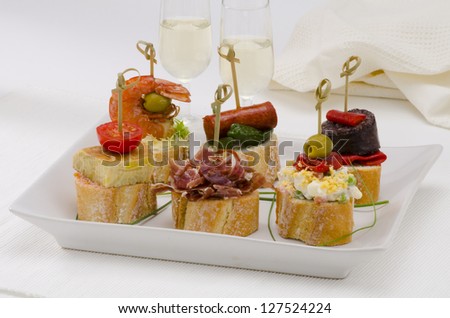 Spanish cuisine. Montaditos. Sliced bread topped with a variety of appetizers. Spanish Tapas. Two glasses of Sherry wine in the background.