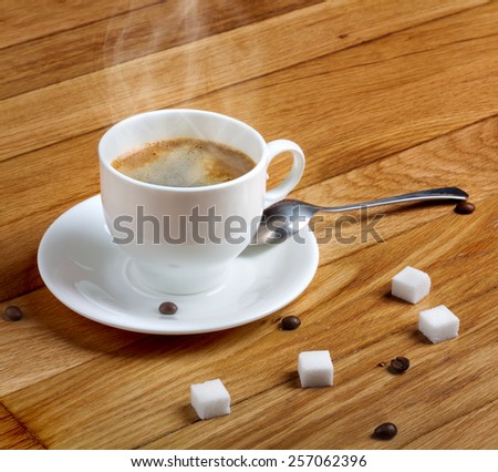 Hot fresh coffee in a white cup with sugar on wooden table