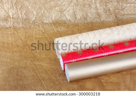 Rolls of multicolored wrapping paper for gifts on gold abstract background. View from above with copy space