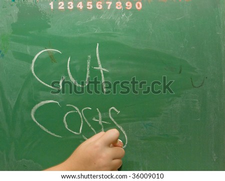 Hand writing cut costs on old green chalkboard.
