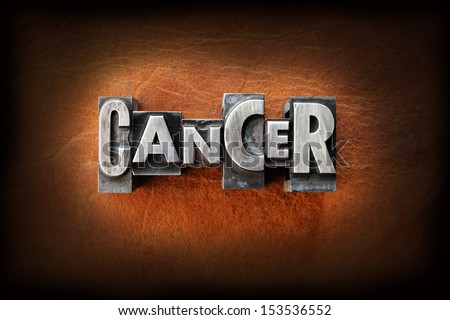 The word cancer made from vintage lead letterpress type on a leather background.
